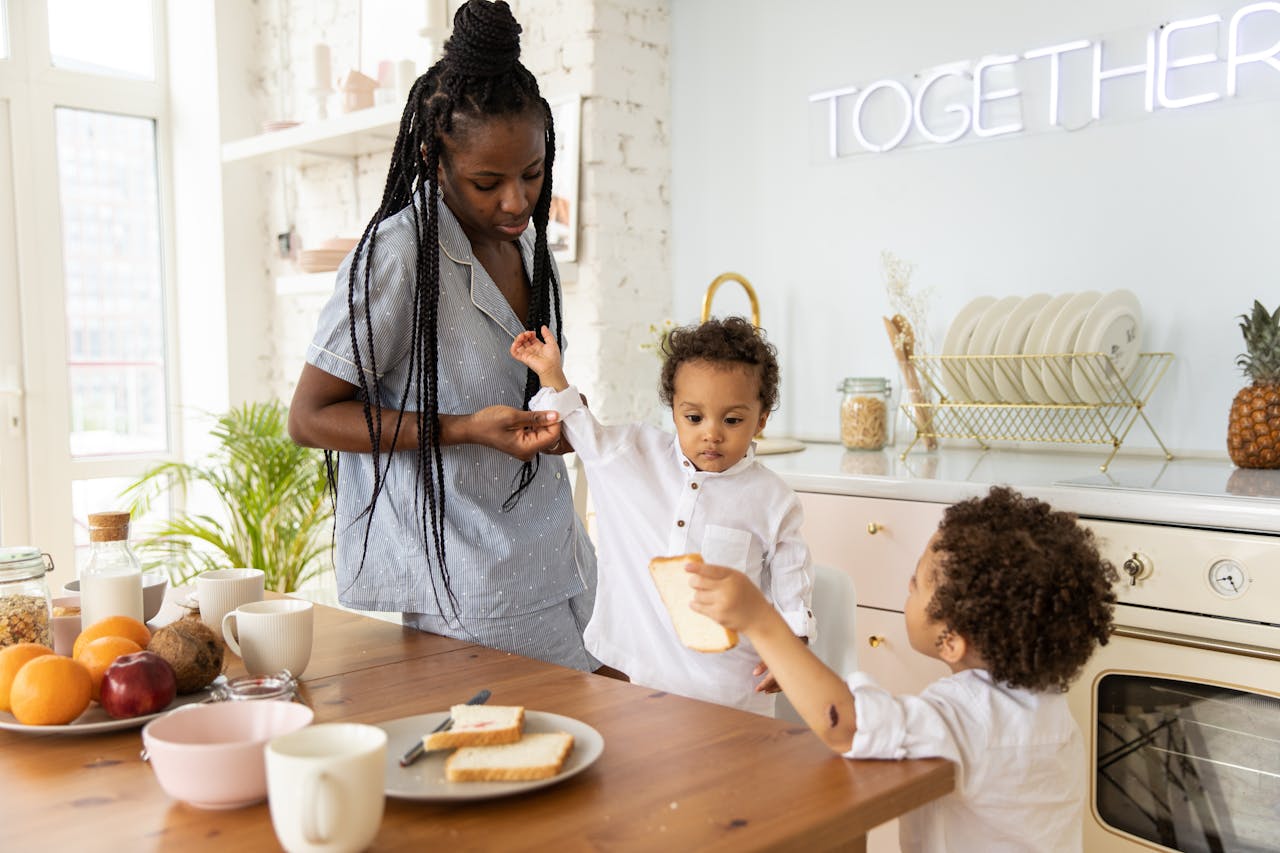 A mother and two children enjoy breakfast together in a warm kitchen setting.